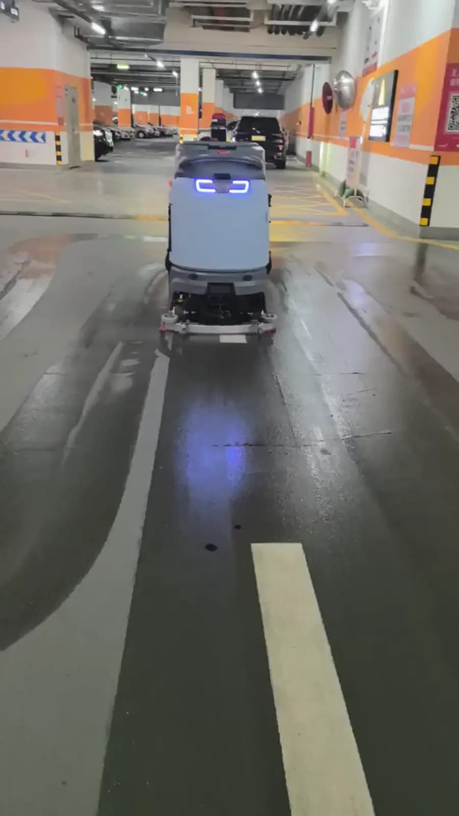 Equipo de limpieza comercial trabajando en un estacionamiento cubierto.