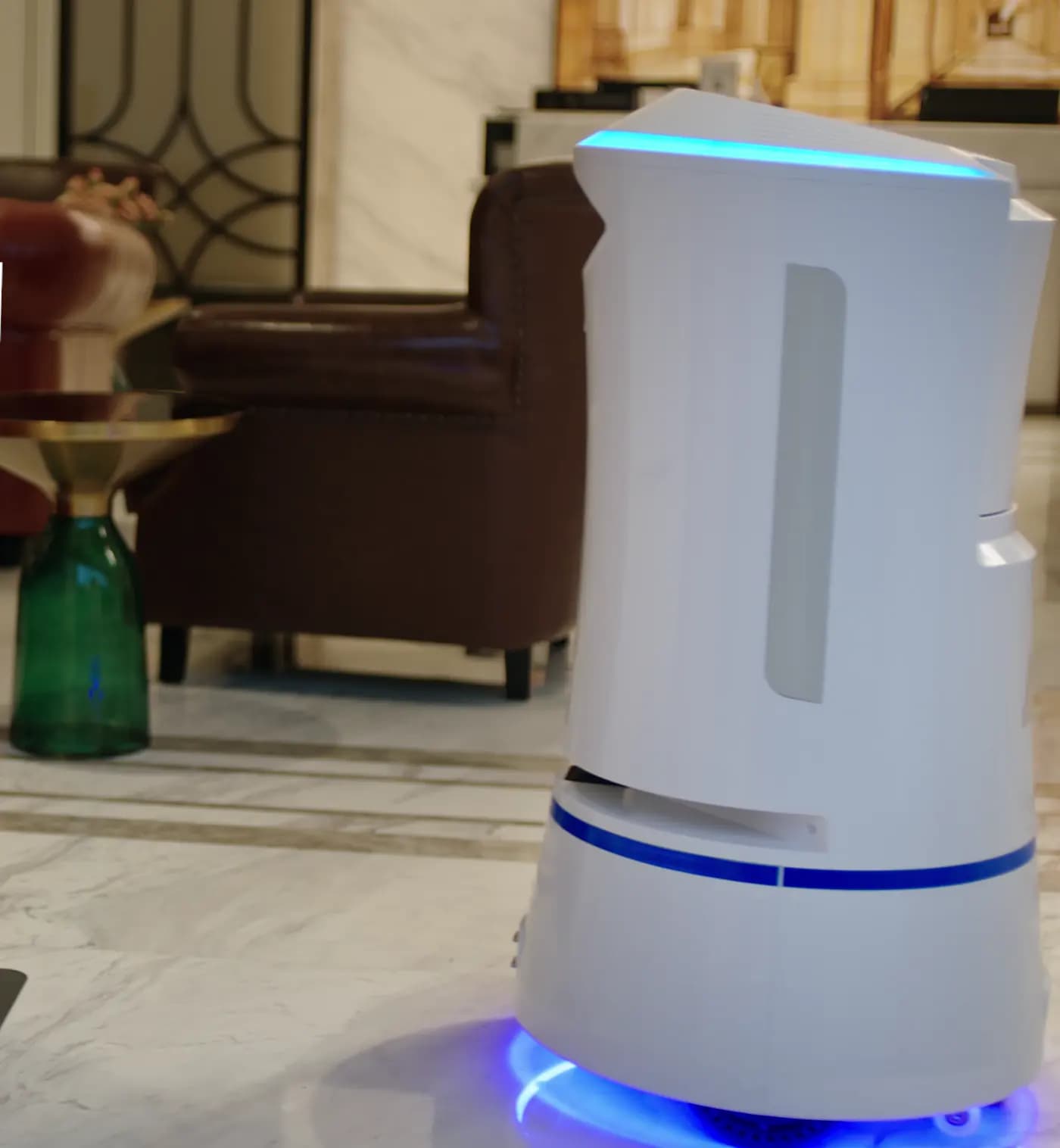 Robot de servicio blanco en un lobby con piso de mármol.